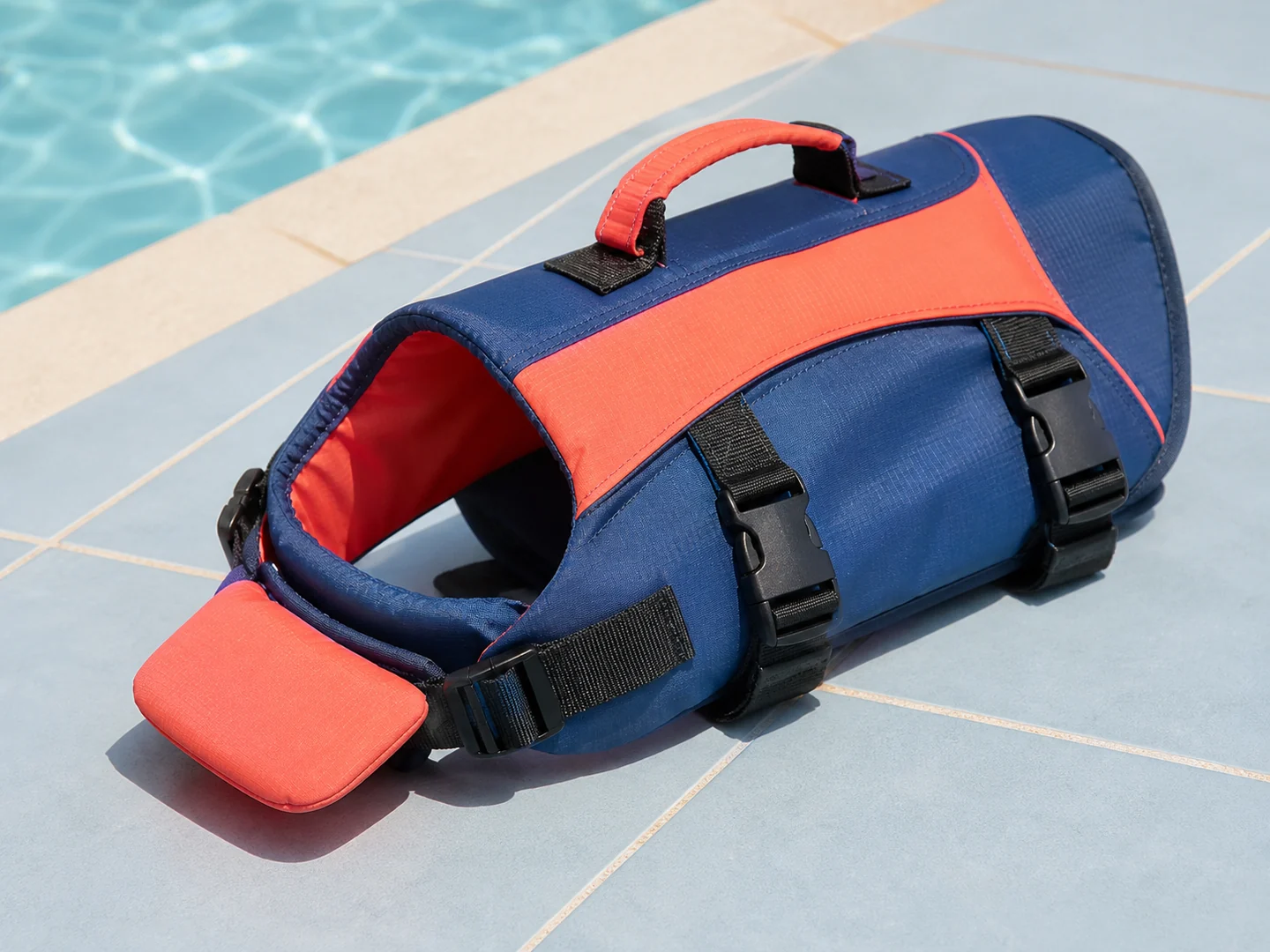 Close view of the navy ChinUp jacket showing the coral chin pad, rescue handle, webbing and quick-release buckles